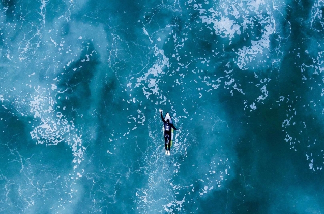 Surfista remando hasta la ola en medio del mar